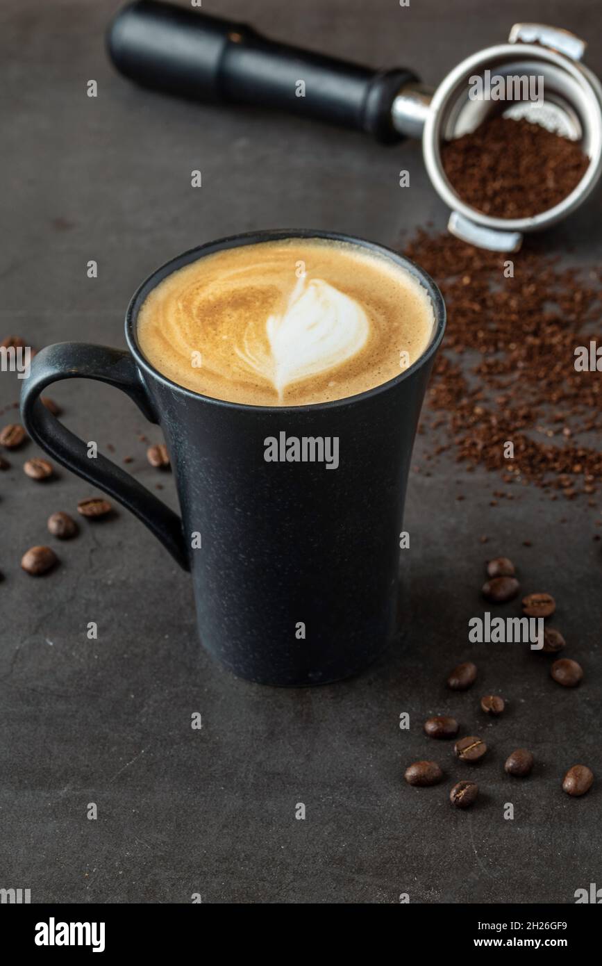 Caffè latte rilassante in una tazza di porcellana nera su un tavolo in pietra Foto Stock
