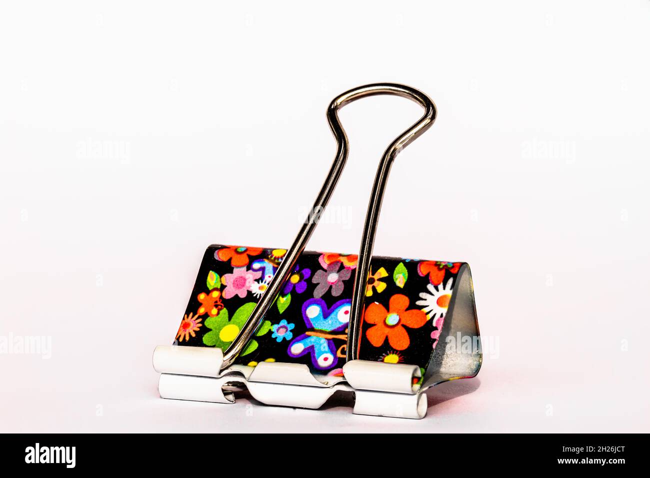 Una clip in carta con motivi floreali metallizzati, isolata su sfondo bianco, per un concetto allegro di ufficio, lavoro, scuola e business Foto Stock