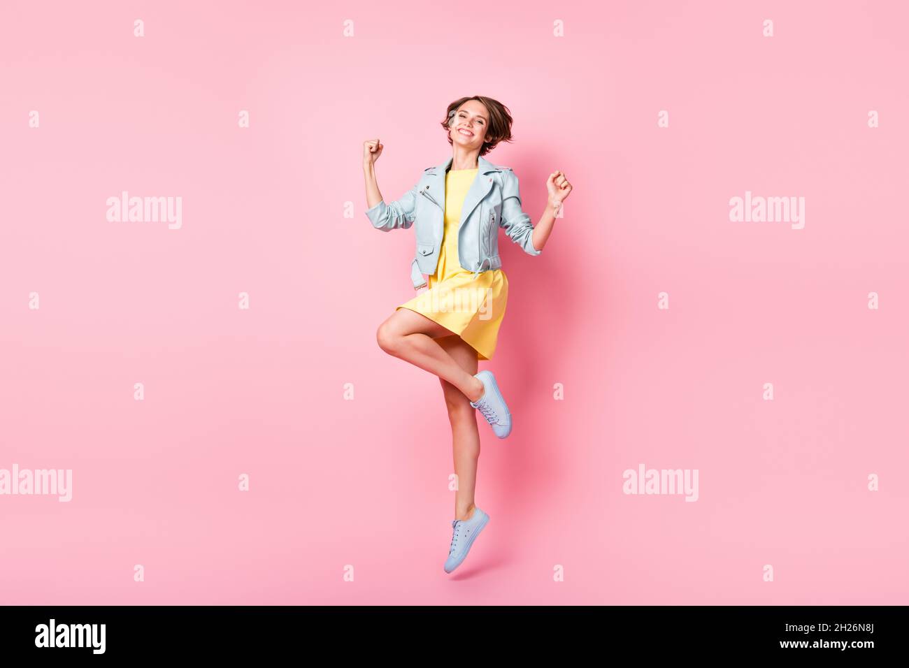 Foto di sognante ispirato lady salto hanno divertimento indossare abiti gialli corto sneakers isolato colore rosa sfondo Foto Stock