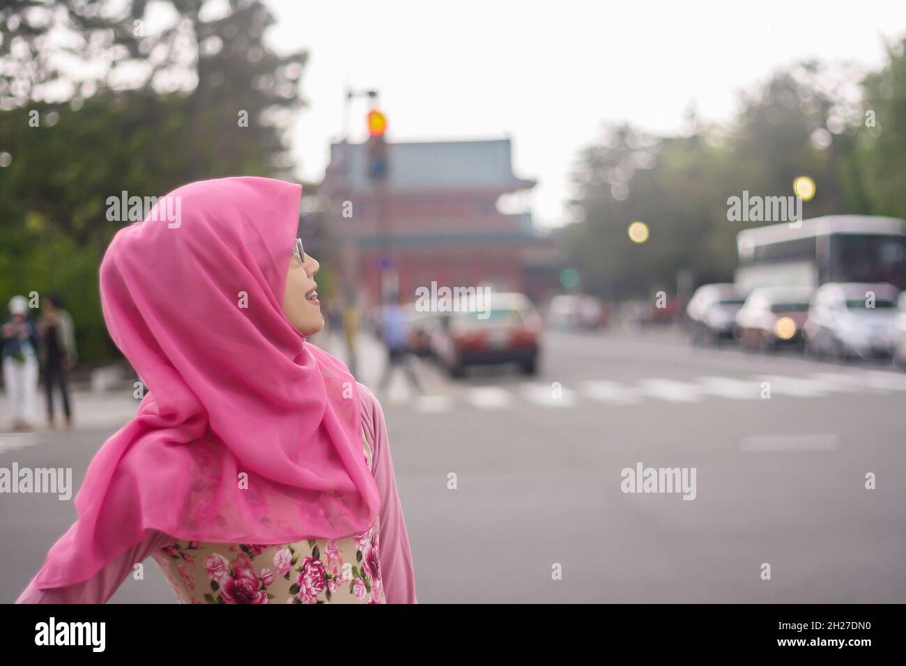 Ritratto di bella giovane musulmana asiatica indossando hijab e occhiali in via di Kyoto. Faccia sorridente e guardando lontano dalla fotocamera. Foto Stock