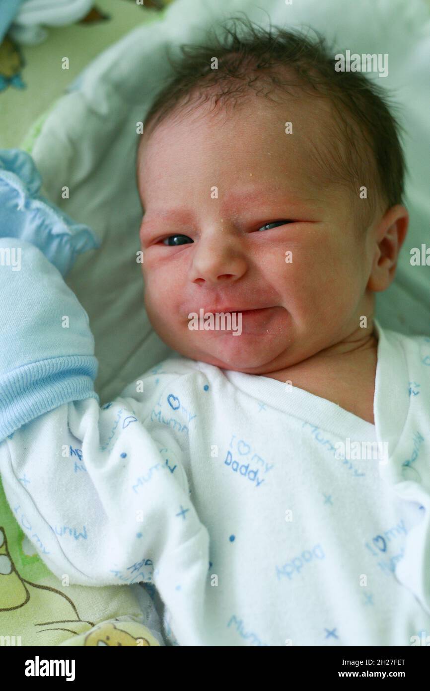Un bambino neonato di un giorno con guanti anti-presa sta