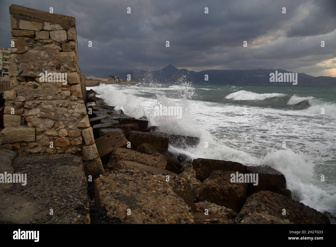 Tempesta in mare, le onde si infrangono sulla costa rocciosa, nuvole grigie pesanti Foto Stock