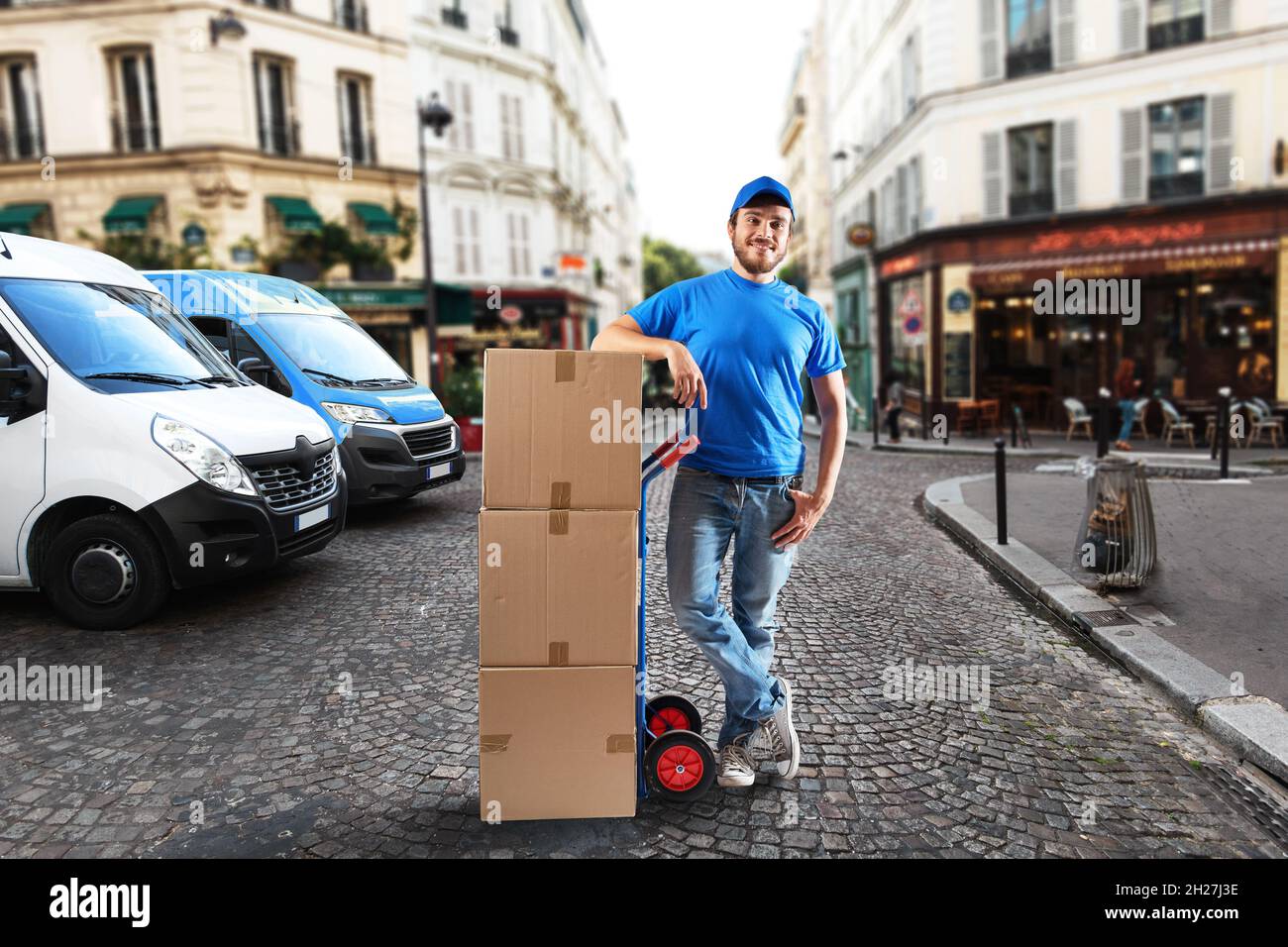 Uomo con uniforme blu davanti ai negozi per la consegna e il ritiro della merce Foto Stock