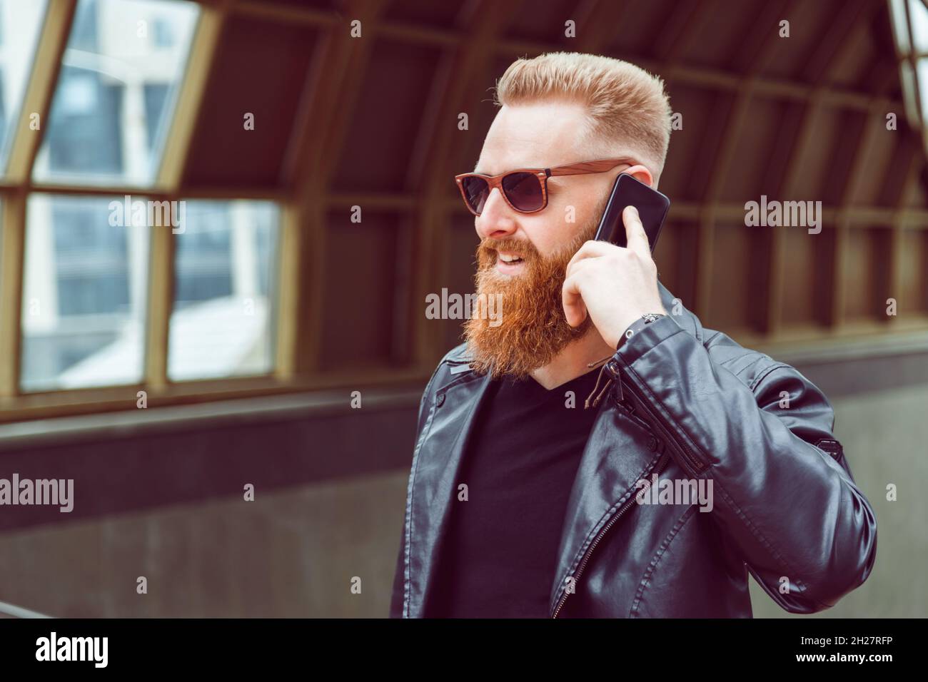 Uomo con capelli rossi in occhiali da sole e giacca in pelle ha  conversazione telefonica Foto stock - Alamy