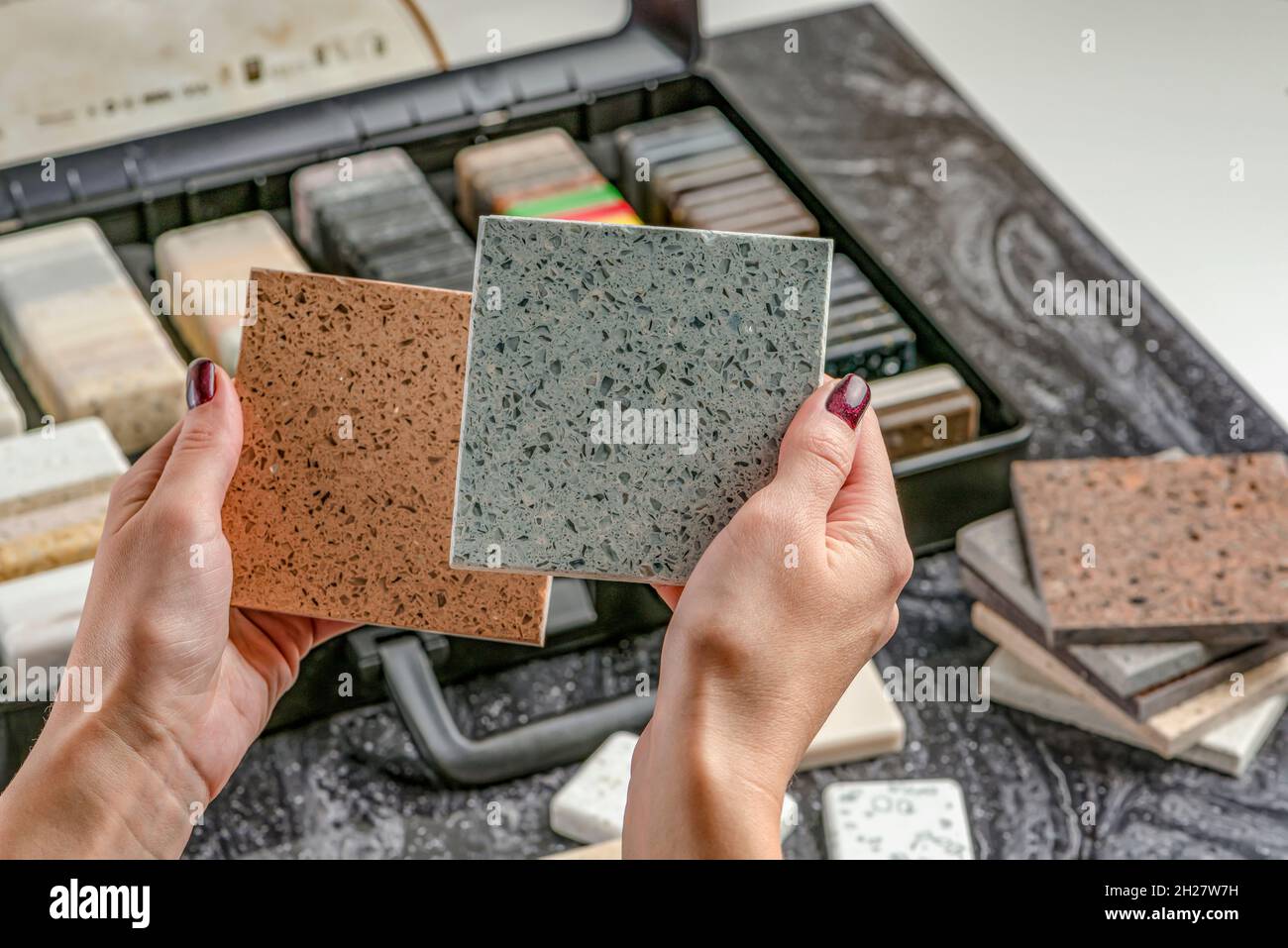 Campioni di materiale per il piano di lavoro. Le mani femminili stanno scegliendo gli elementi interni per la ristrutturazione. Campioni di pietra acrilica in mani. Foto Stock