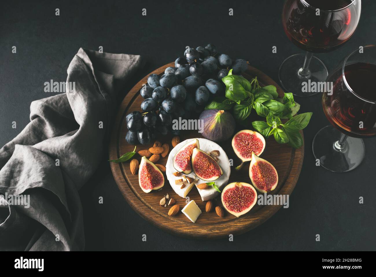 Formaggio bianco brie o camembert con fichi e uva su tavola di legno, servito con un bicchiere di vino. Immagine in tonalità della vista dall'alto. Set di antipasti a base di formaggio e vino Foto Stock
