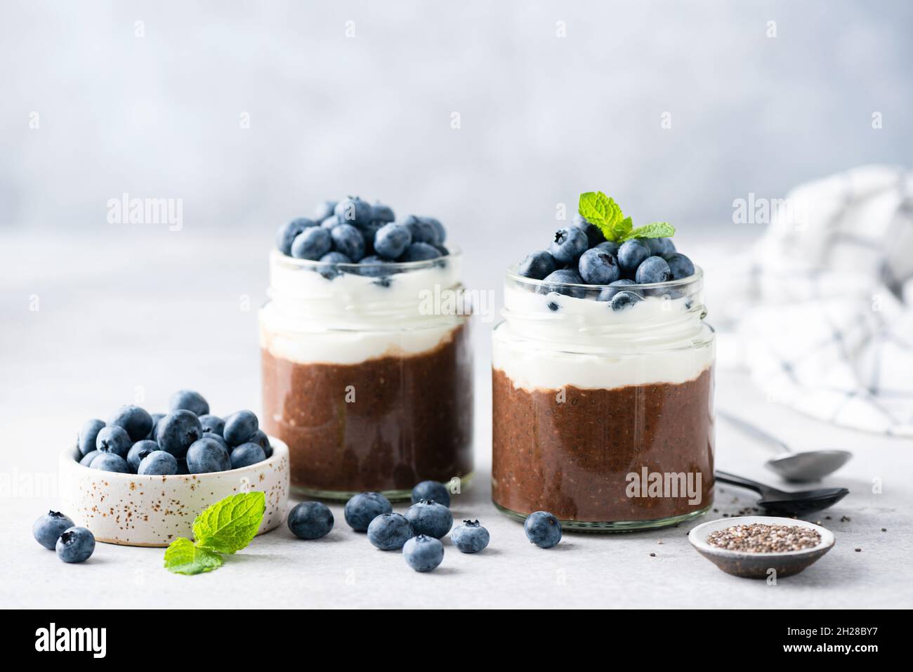 Budino di semi di Chia con cacao e yogurt in un vaso su sfondo grigio di cemento. Snack alimentari vegetariani sani Foto Stock
