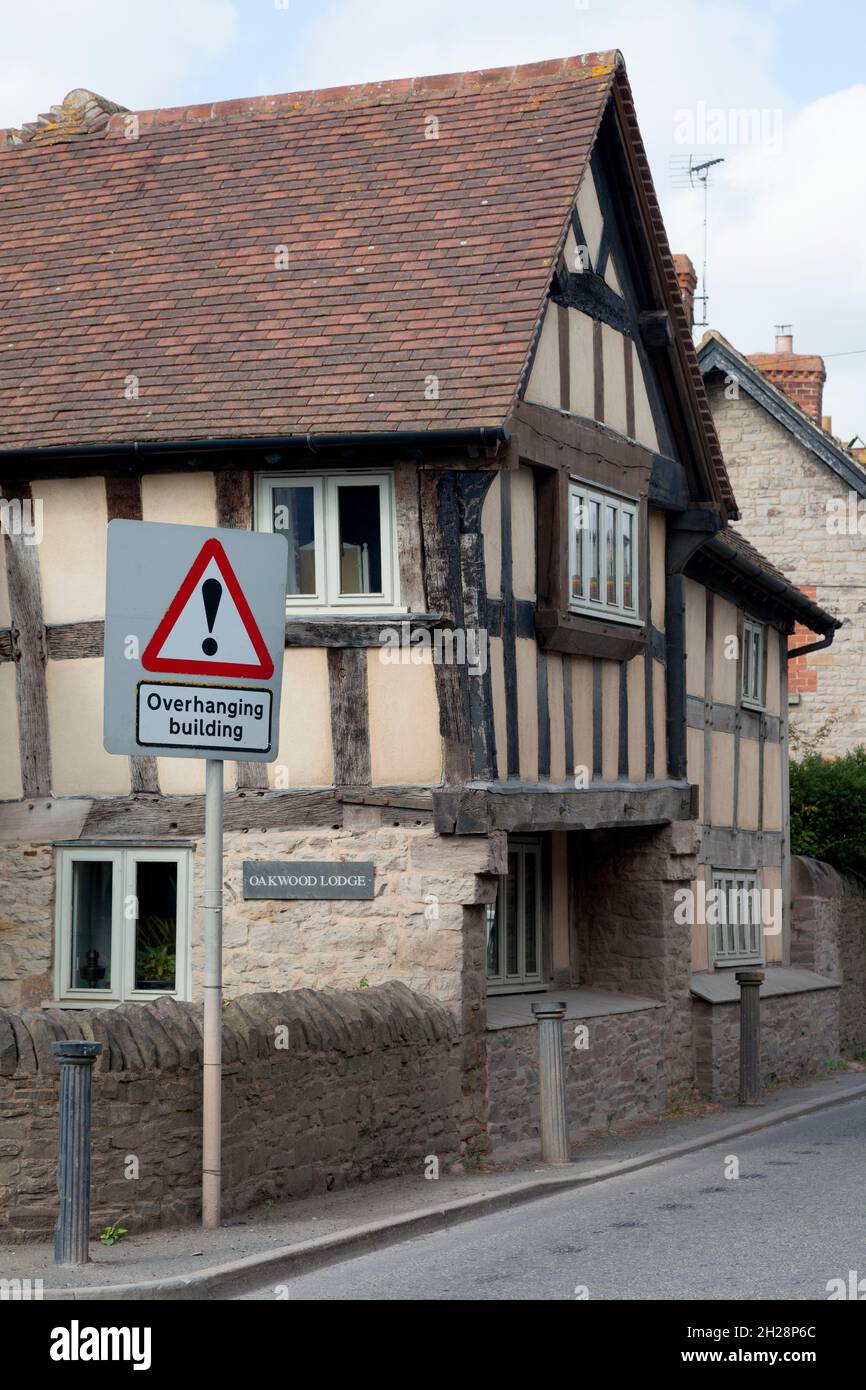 Casa a graticcio in colori originali non dipinti, con 'edificio sospeso' segnaletica stradale, Eardisley, Herefordshire Foto Stock