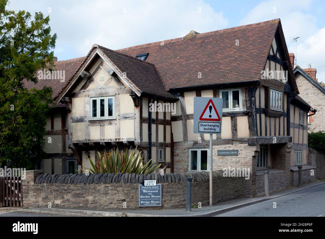 Casa a graticcio in colori originali non dipinti, con 'edificio sospeso' segnaletica stradale, Eardisley, Herefordshire Foto Stock