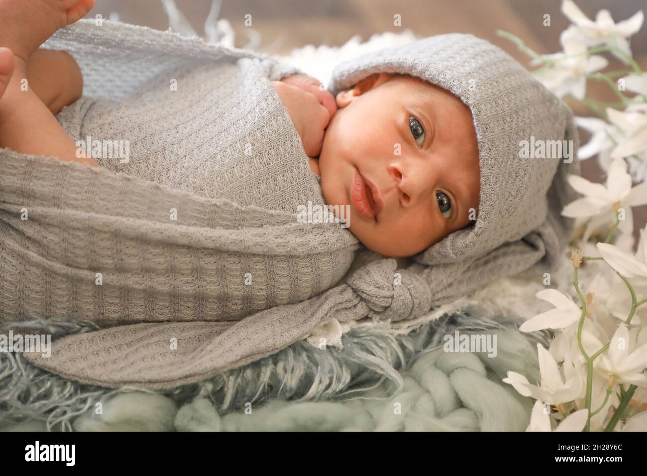 6 mesi bambina dolce arabo musulmana ragazza che posa e posa su una comoda lana cute viso vista dall'alto ritratto grigio sciarpa morbida Foto Stock