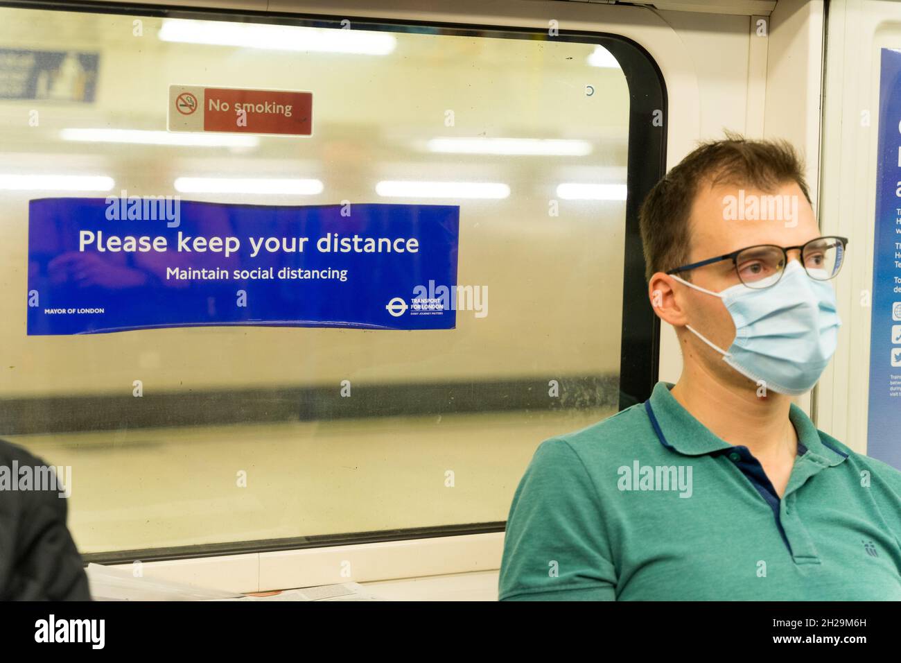 Maschile Racelle a londra metropolitana treno si trova accanto alla finestra dove un cartello 'si prega di mantenere la vostra distanza' Inghilterra Regno Unito Foto Stock