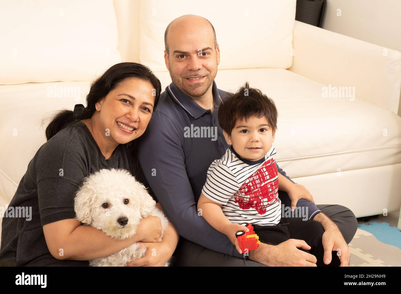 Ritratto di famiglia ragazzo di 2 anni con i genitori e cane da compagnia Foto Stock