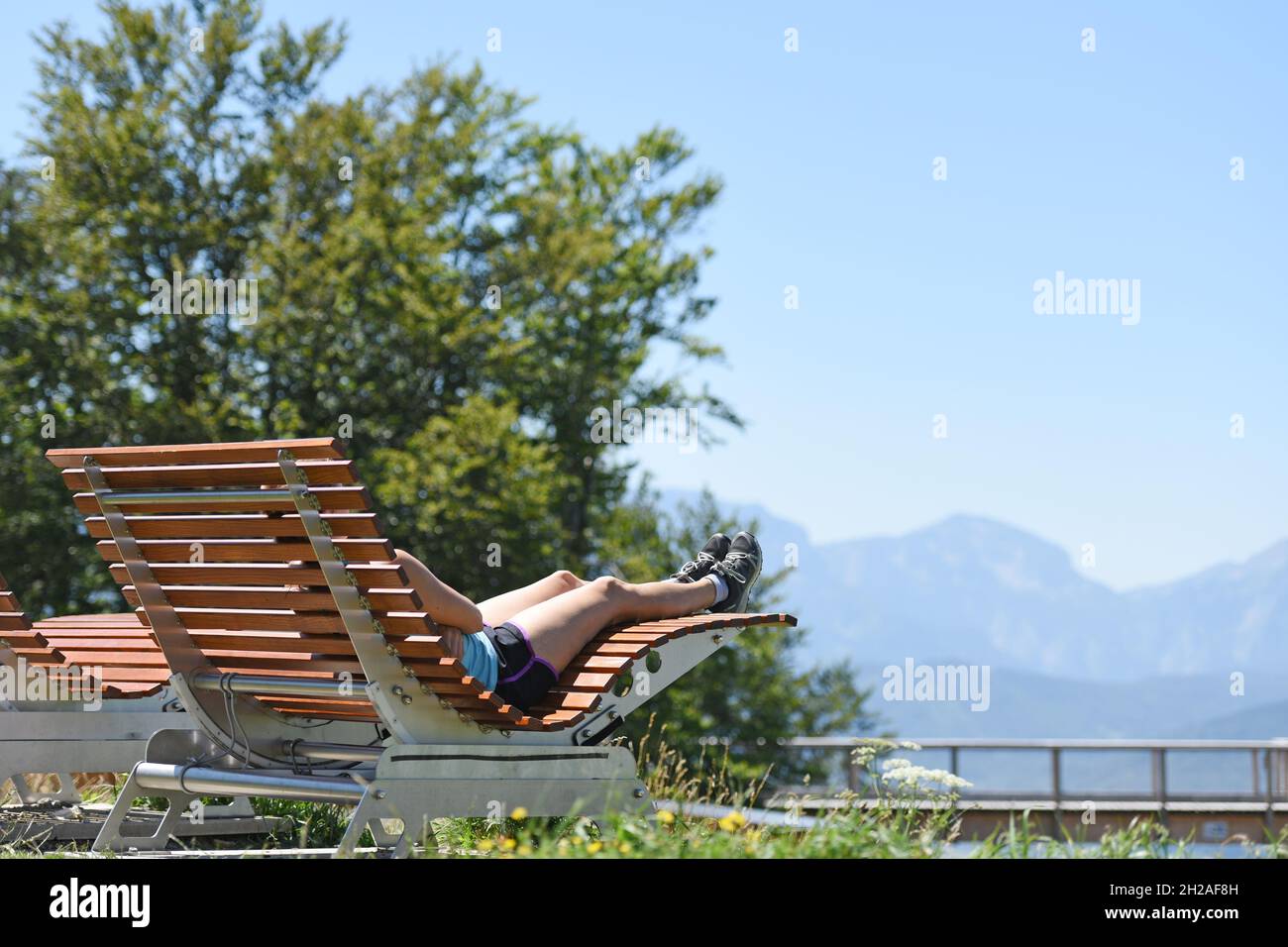 Eine junge Frau erholt sich auf einer Liege auf dem Grünberg bei Gmunden (Salzkammergut; Oberösterreich; Österreich) von der Anstrengung des Anstiegs. Foto Stock