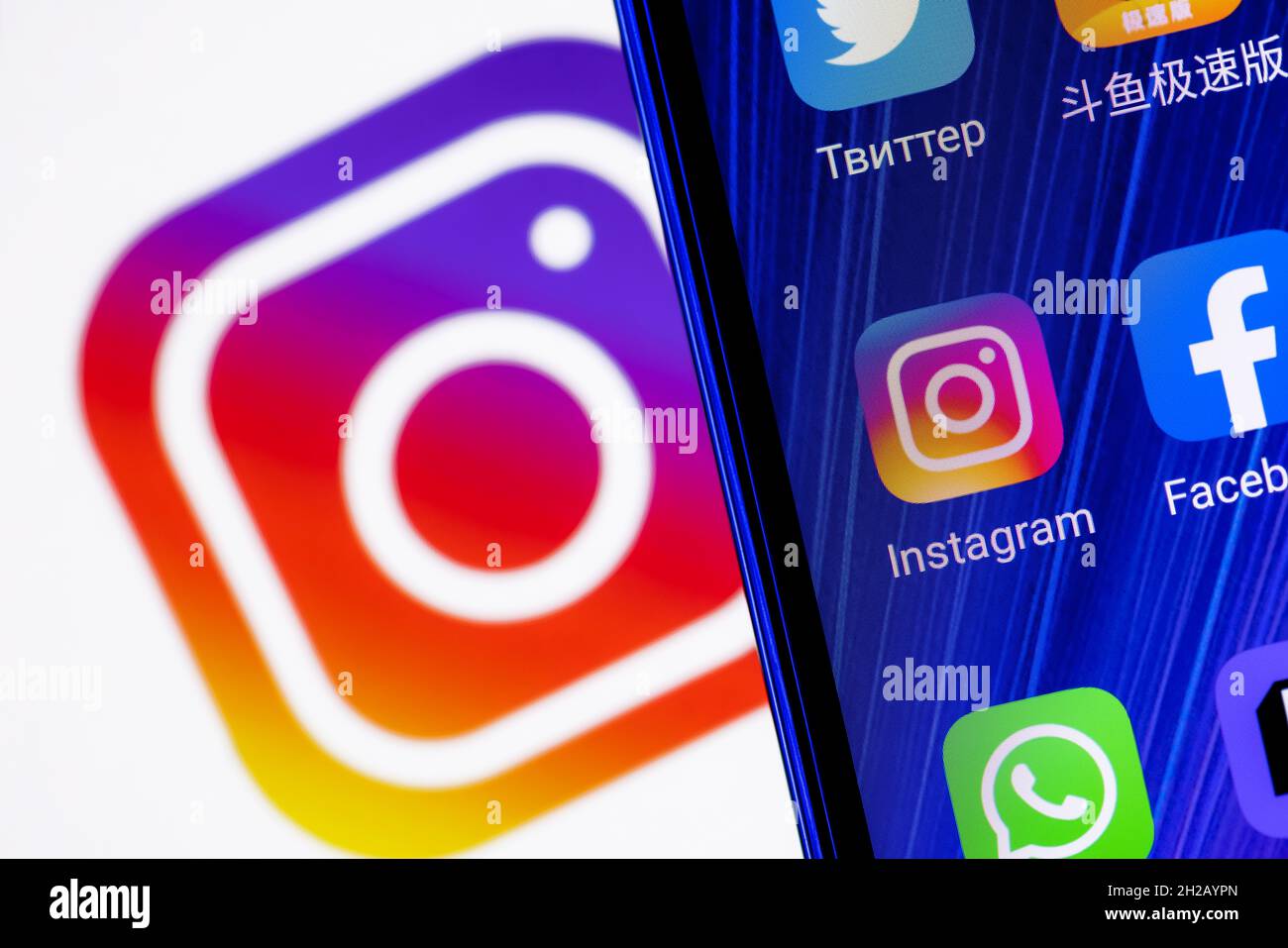 L'icona dell'applicazione di social network Instagram tra le altre applicazioni sullo schermo dello smartphone. Sullo sfondo c'è il logo Instagram. Foto Stock