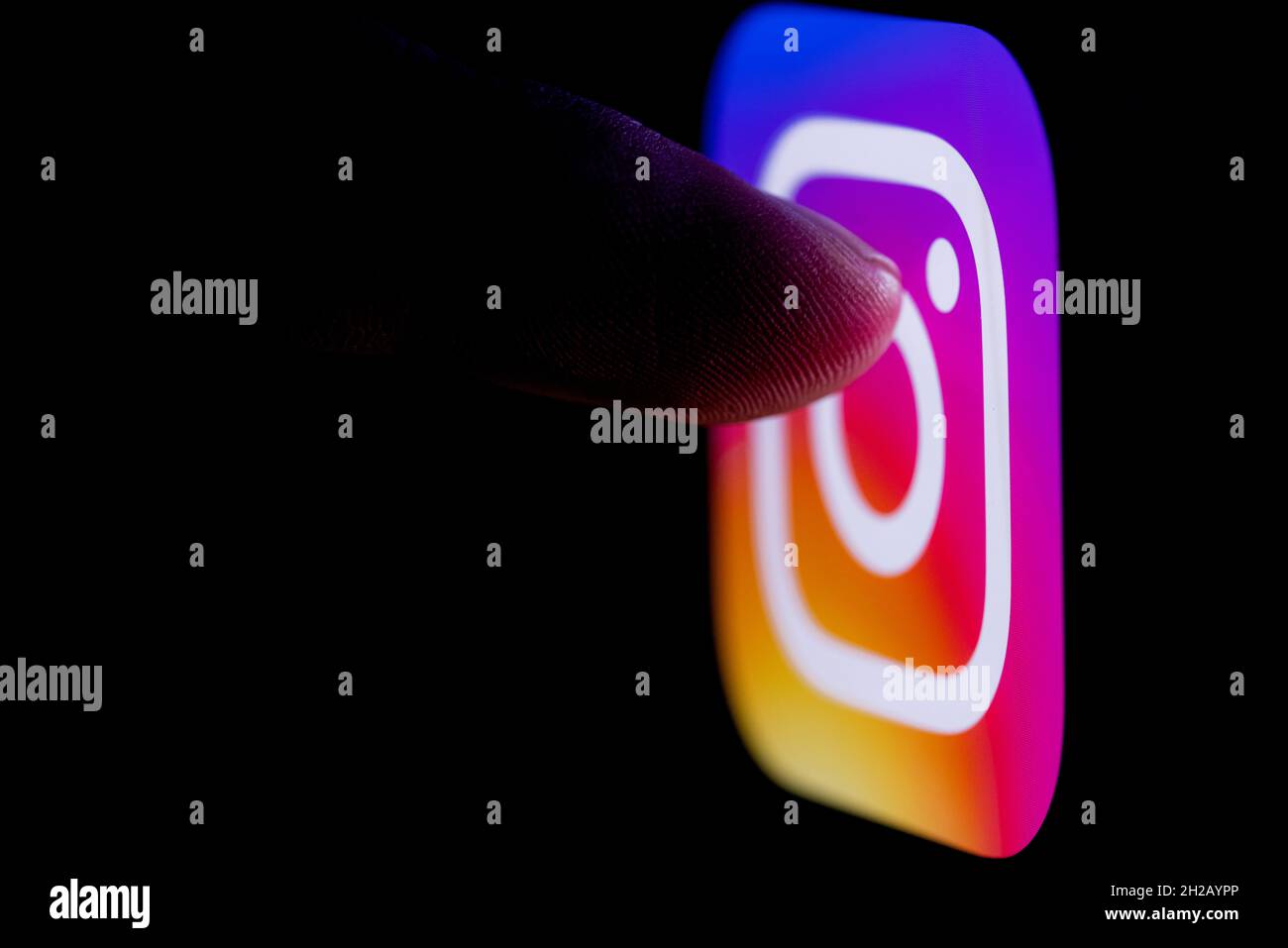 Il dito raggiunge il logo del social network Instagram sullo schermo dello smartphone. Foto Stock