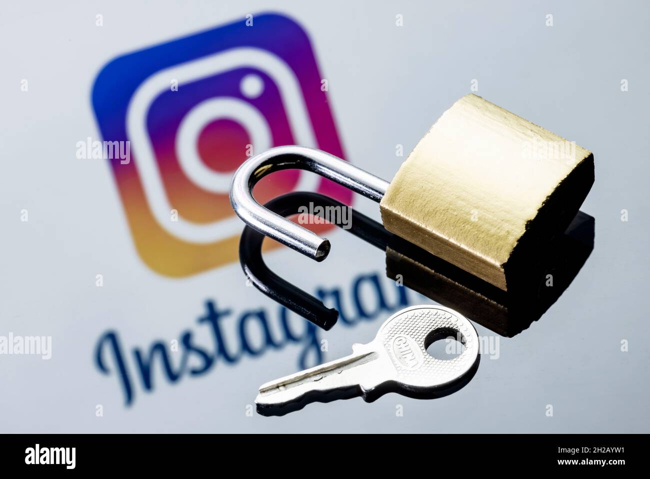 Un lucchetto di sicurezza aperto e una chiave sullo sfondo del logo del social network Instagram nella riflessione speculare. Foto Stock