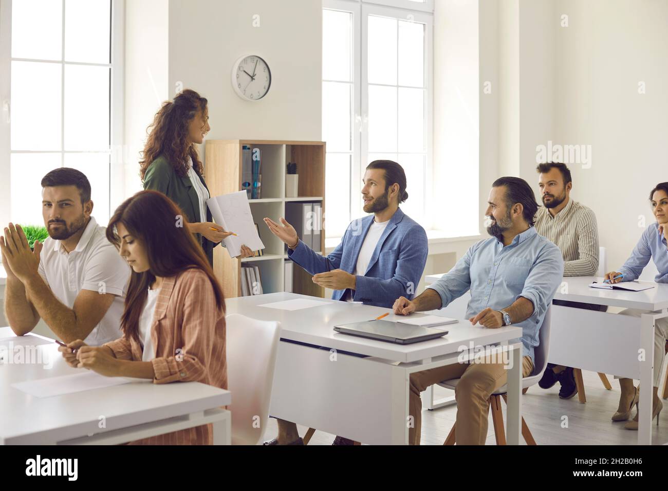 Lo studente maschio adulto risponde alle domande dell'insegnante mentre si siede in una lezione di classe. Foto Stock