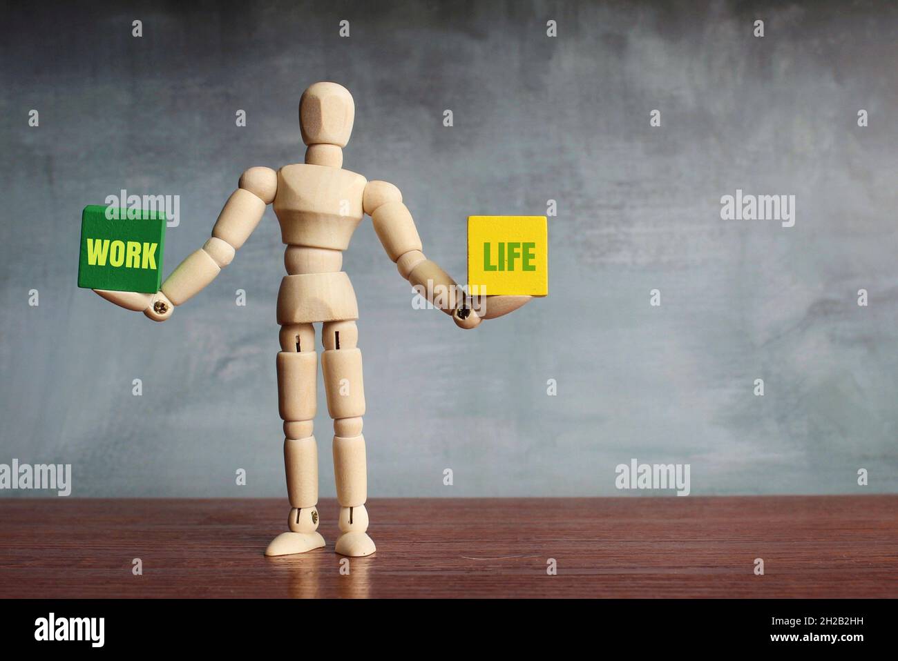 Concetto di equilibrio della vita lavorativa. Figura umana in legno che bilancia due blocchi di legno con il lavoro di testo e LA VITA Foto Stock