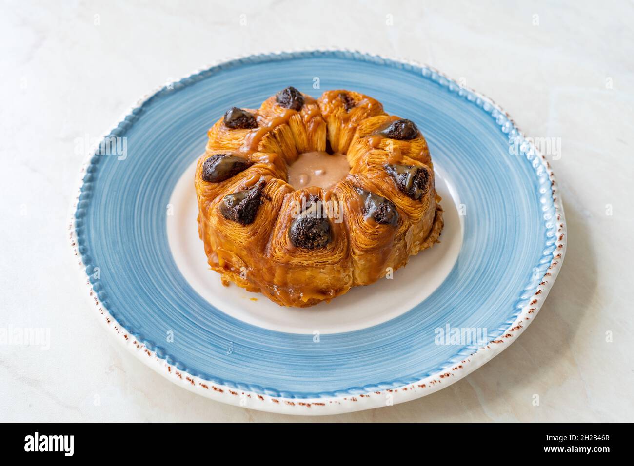 Croissant rotondo con praline pralina al cioccolato in piatto. Pronto a mangiare. Foto Stock