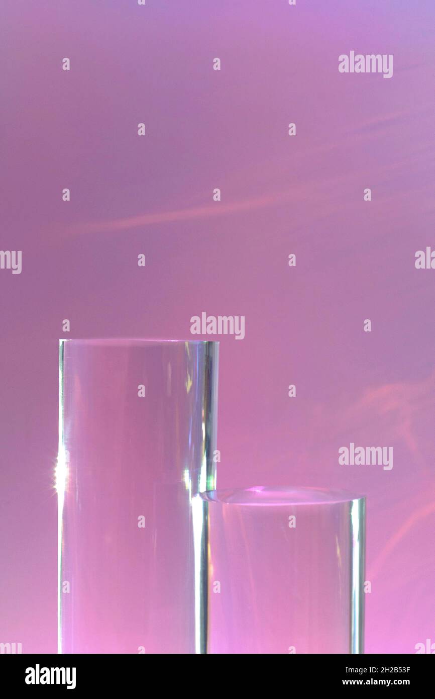 due podi in vetro trasparente su sfondo rosa pastello Foto Stock