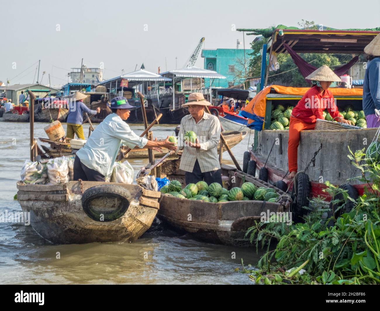 I locali commerciano merci dalle loro barche nel mercato galleggiante sul delta del fiume Mekong - Cai Rang, Vietnam Foto Stock