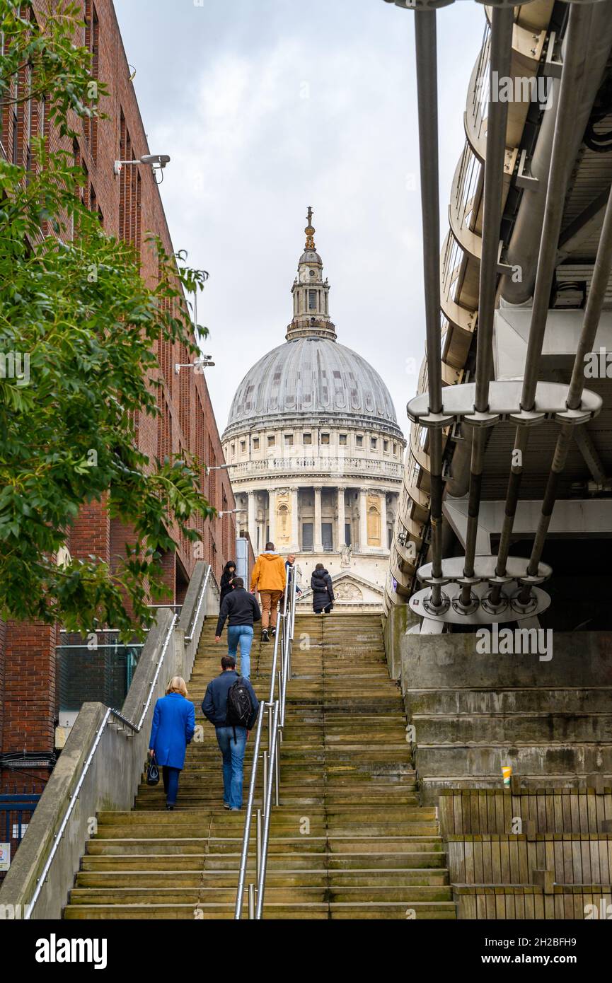 La Cattedrale di St Paul appare tra un edificio e il Millennium Bridge con gente che cammina fino a Peter's Hill, Londra, Inghilterra. Foto Stock