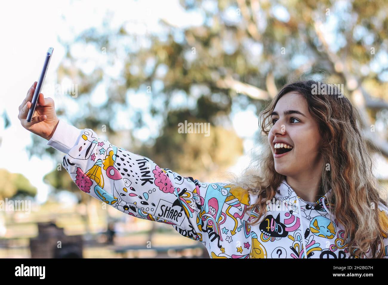 Ragazza sorridente graziosa che prende un selfie. Giovane ragazza all'aperto Foto Stock