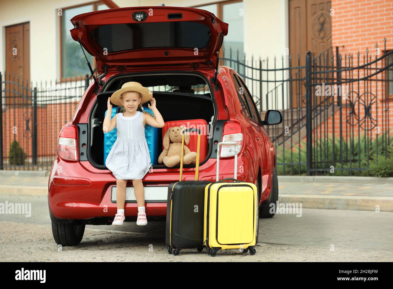Bambina seduta nel bagagliaio con valigie all'aperto. Spazio per il testo  Foto stock - Alamy