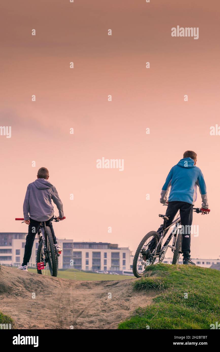 Due ragazzi in bicicletta su una pista sabbiosa a Fistral a Newquay in Cornovaglia. Foto Stock