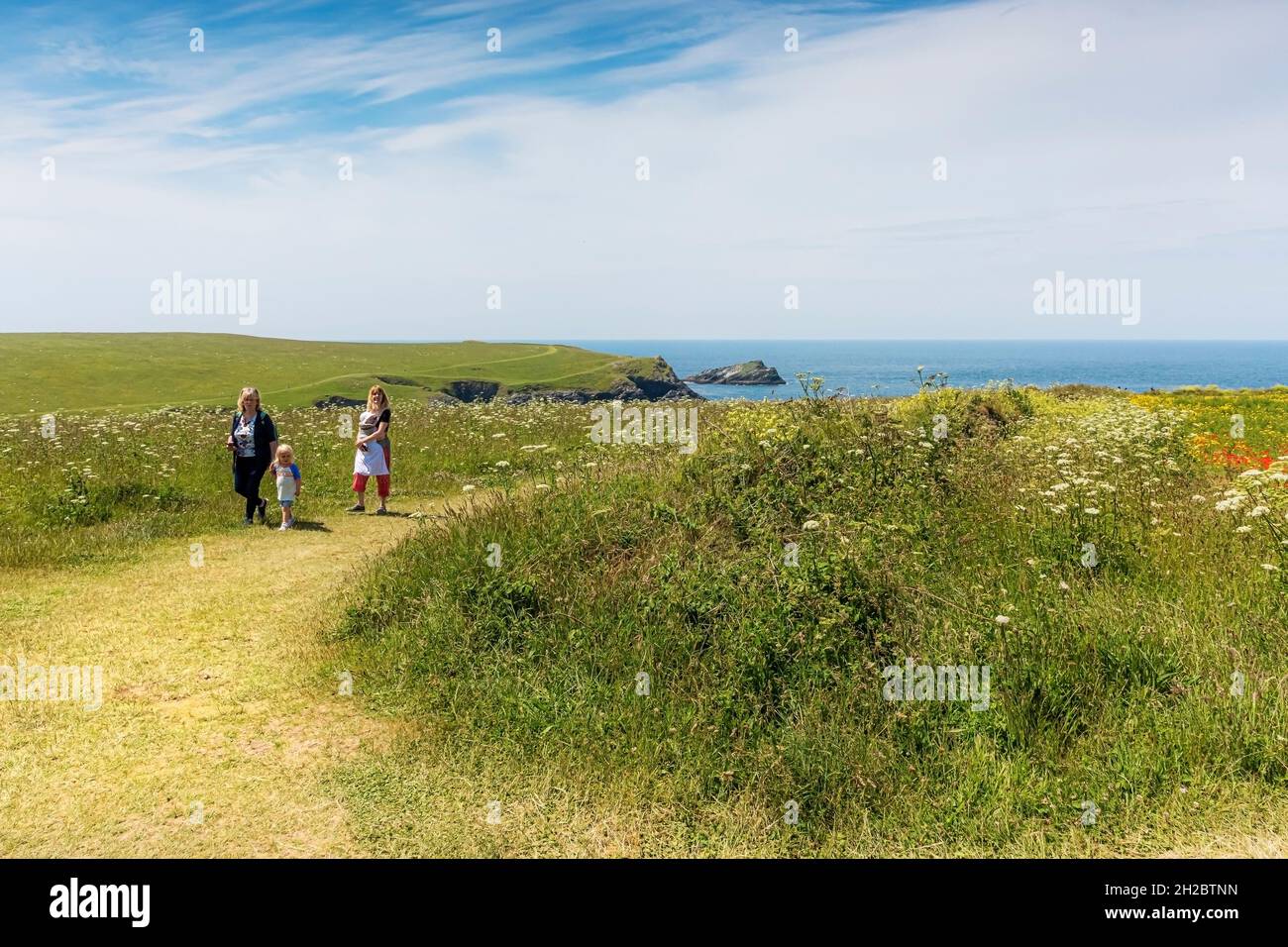 Adulti e bambini si godono una passeggiata attraverso i campi arabili sulla costa di West Pentil a Newquay in Cornovaglia. Foto Stock