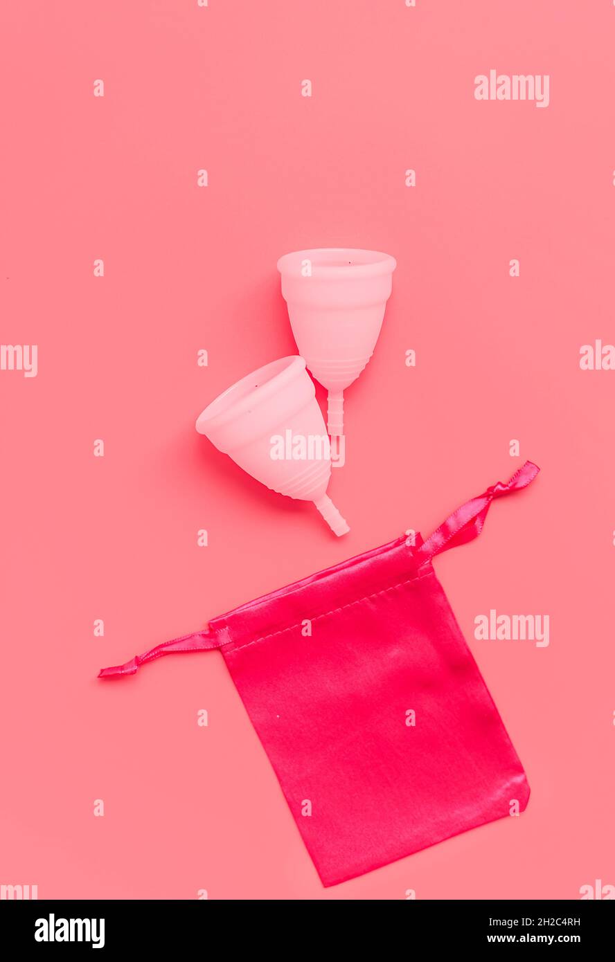 Tazza mestruale rosa su sfondo colorato, prodotti per il periodo dell'igiene intima femminile, vista dall'alto Foto Stock