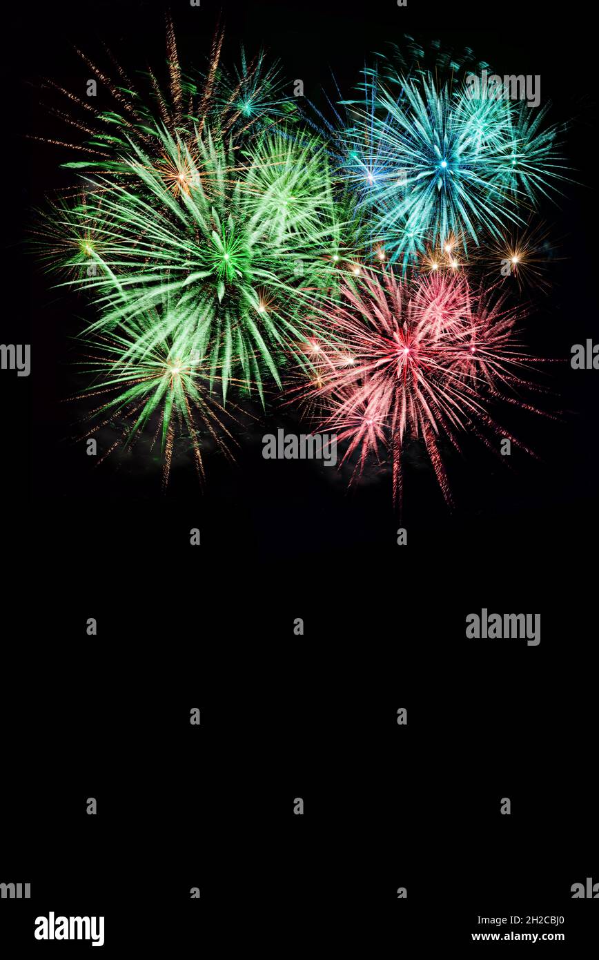 Fuochi d'artificio colorati in un cielo notturno nero. Sfondo pirotecnico per biglietto di auguri o poster di festa. Formato verticale con copia sp Foto Stock