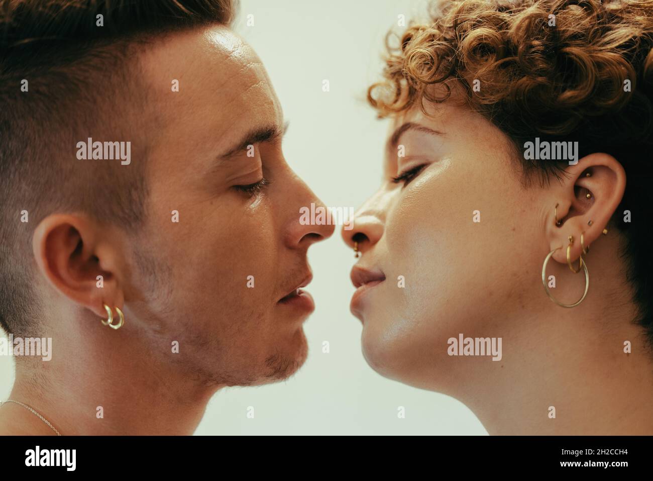 Coppia romantica che va in per un bacio. Affettuoso giovane coppia queer in piedi l'uno vicino all'altro con gli occhi chiusi. Giovane coppia LGBTQ+ in condivisione Foto Stock