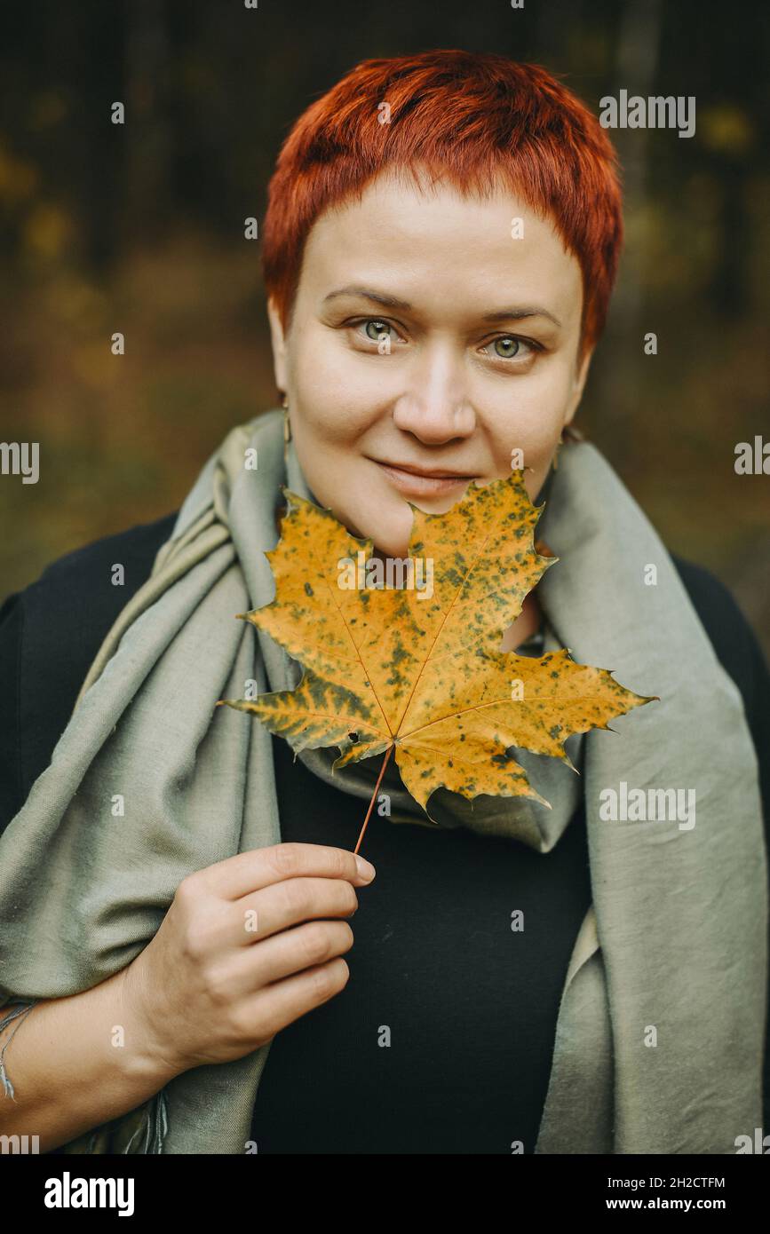 Donna di mezza età con foglia d'acero d'autunno Foto Stock