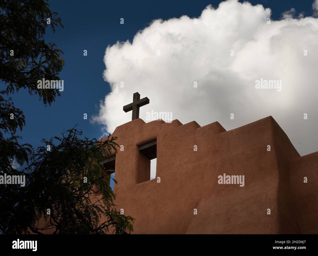 Una croce sulla cima di una storica chiesa di adobe a Santa Fe, New Mexico. Foto Stock