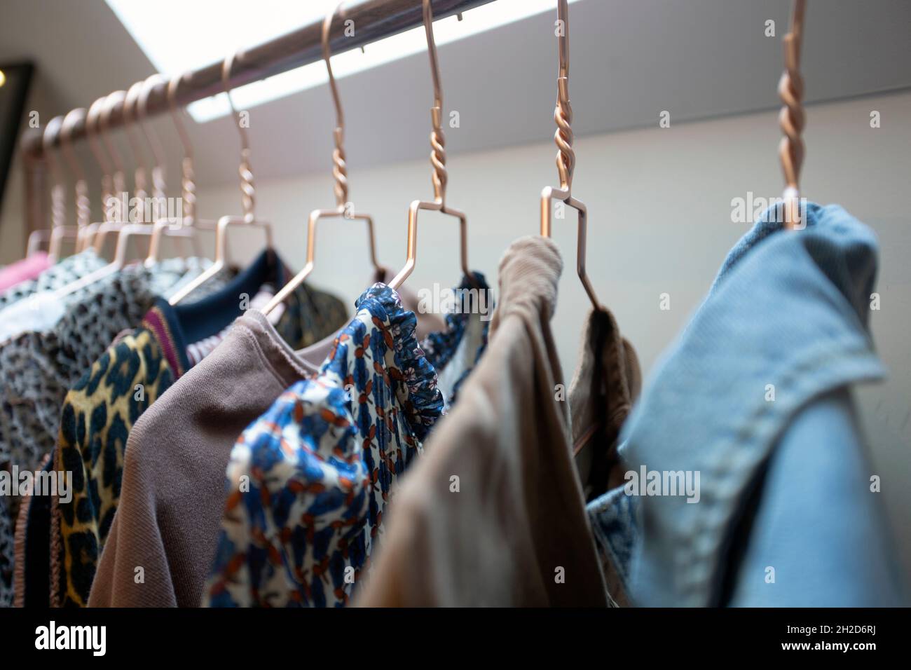 Appende su scaffale con colorati abiti alla moda in camera moderna. Interni della casa, moda e concetto di stoccaggio Foto Stock