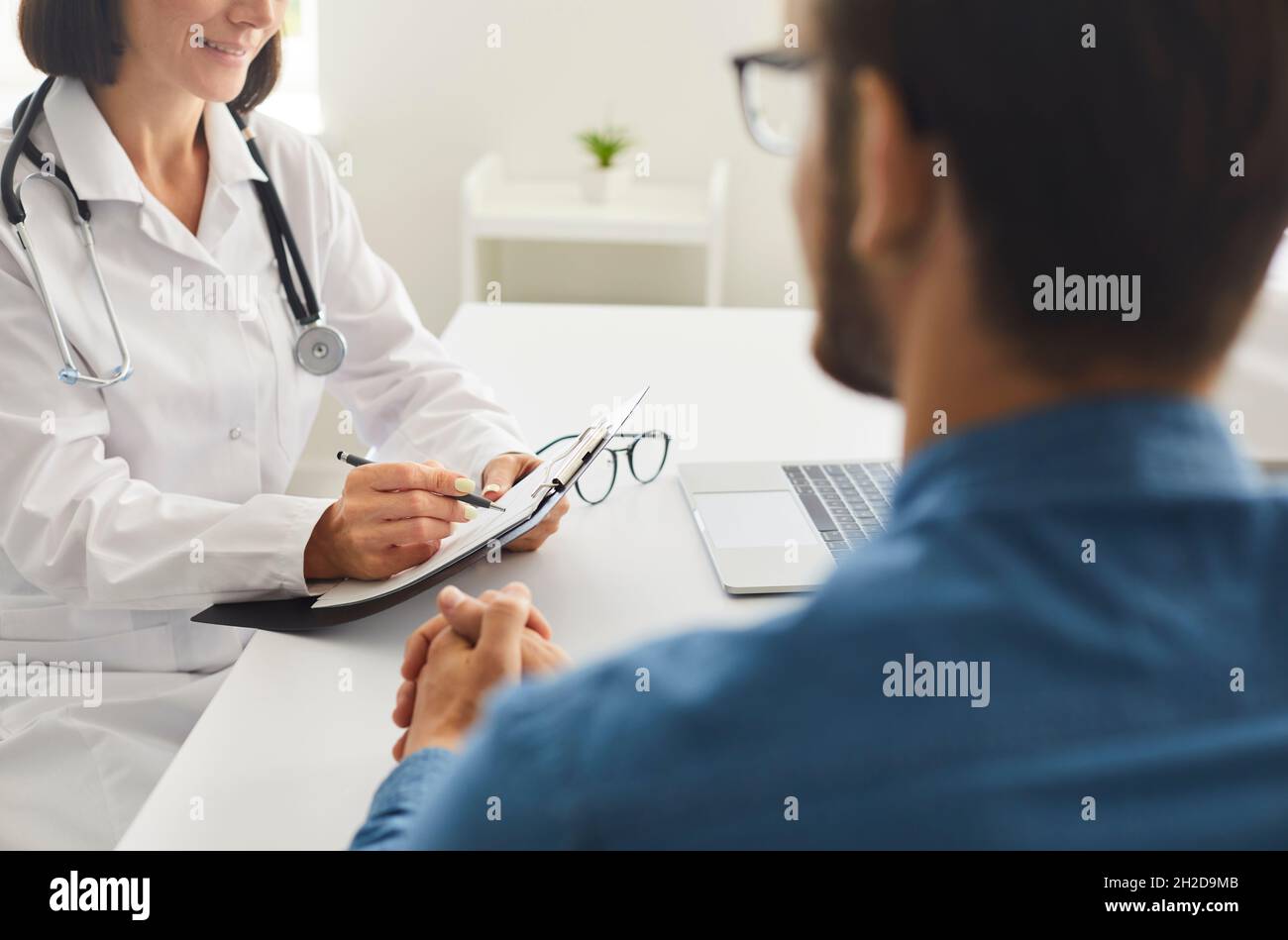 Medico seduto alla scrivania, che parla con la paziente e gli prescrive il trattamento Foto Stock