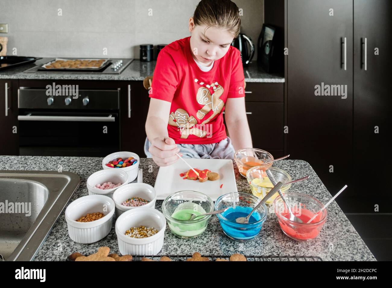 Giovane ragazza che decora i biscotti di pan di zenzero di natale Foto Stock