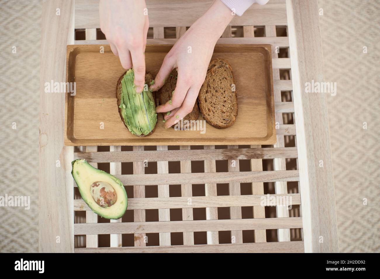 Vista dall'alto della giovane donna taglia l'avocado a fette Foto Stock