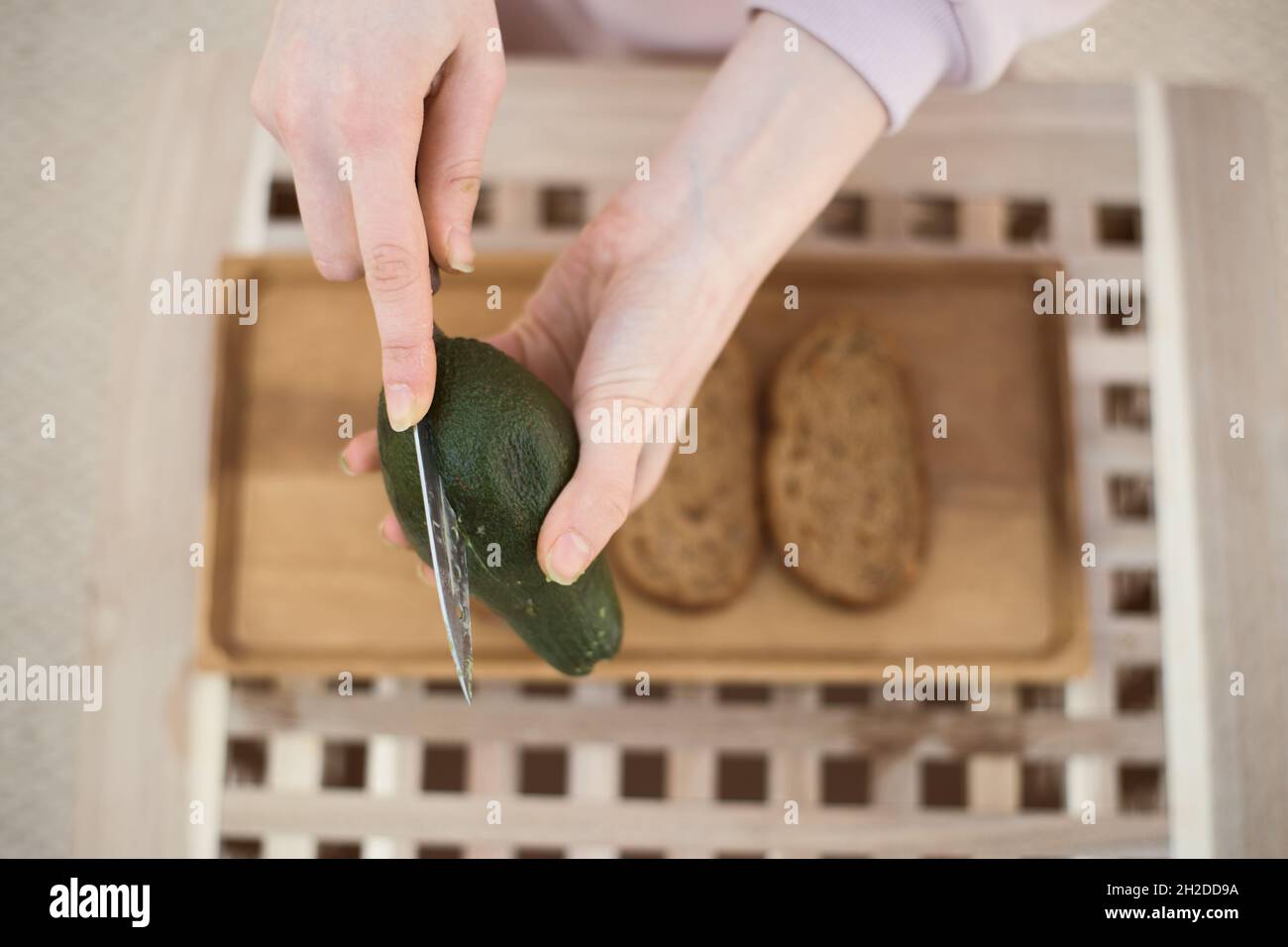 Vista dall'alto delle giovani mani femmine taglio avocado a metà Foto Stock