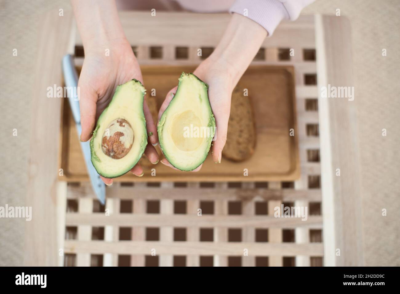 Vista dall'alto dell'avocado dimezzato nelle mani delle giovani donne Foto Stock