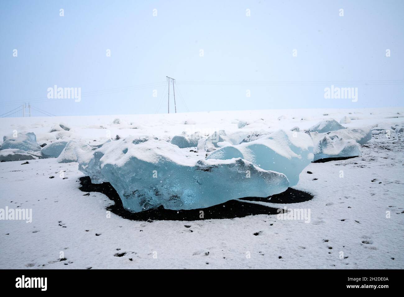 Vista del paesaggio di pezzi di ghiacciaio su terreno nevoso con ombra sotto il cielo blu in una giornata di sole in Islanda Foto Stock
