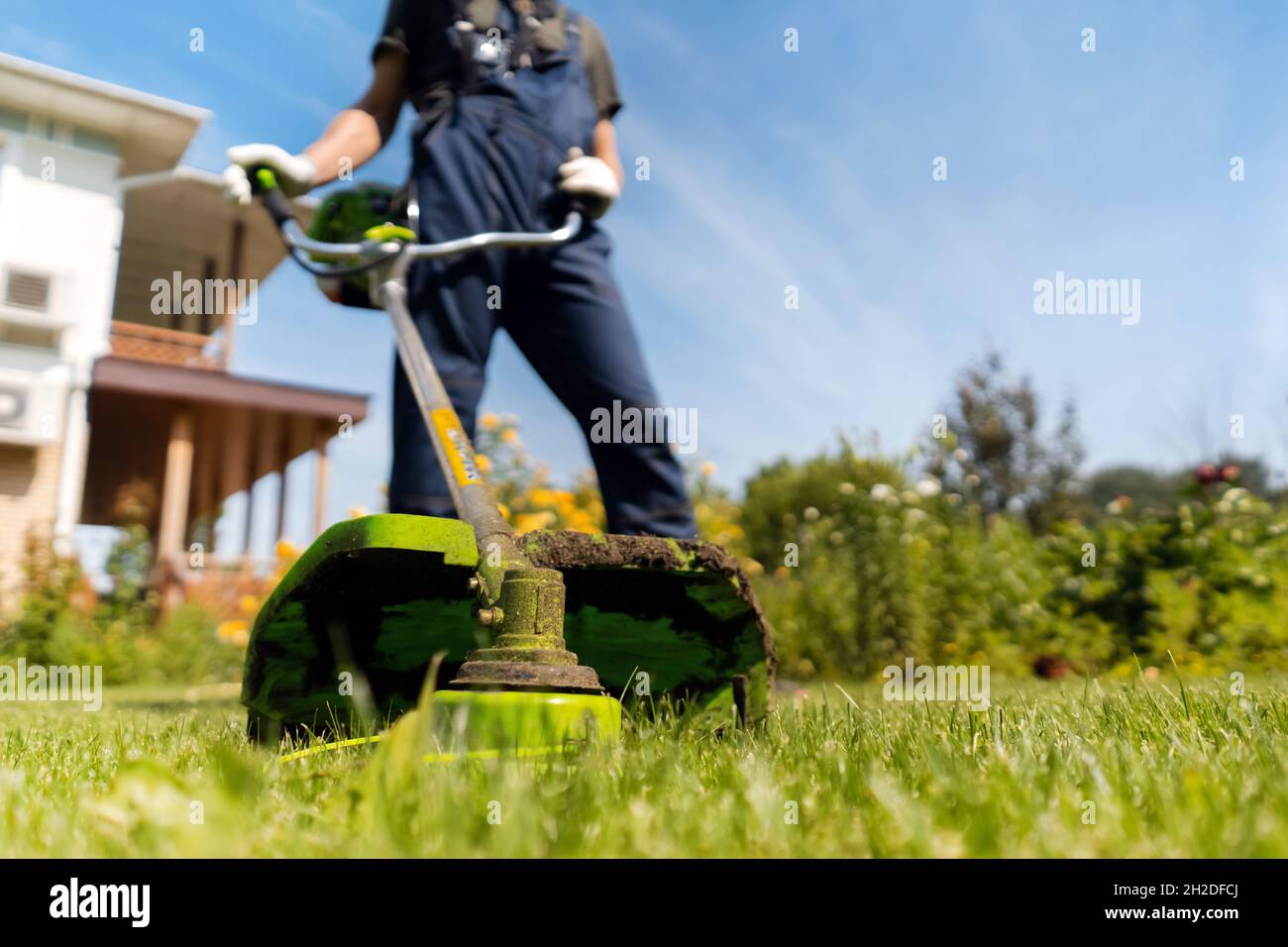 Il giardiniere sta falciando un prato in una giornata di sole. Foto Stock