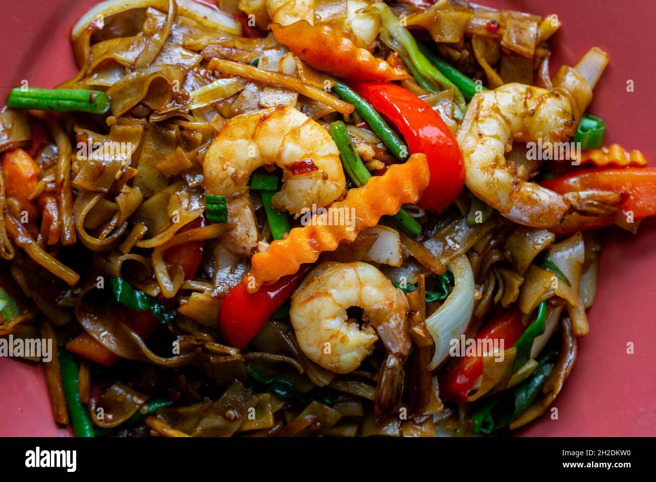 Spaghetti ubriachi, pad kee mao, con gamberi, basilico, peperoncini, peperoni e fagioli verdi. Primo piano su una piastra. Foto Stock