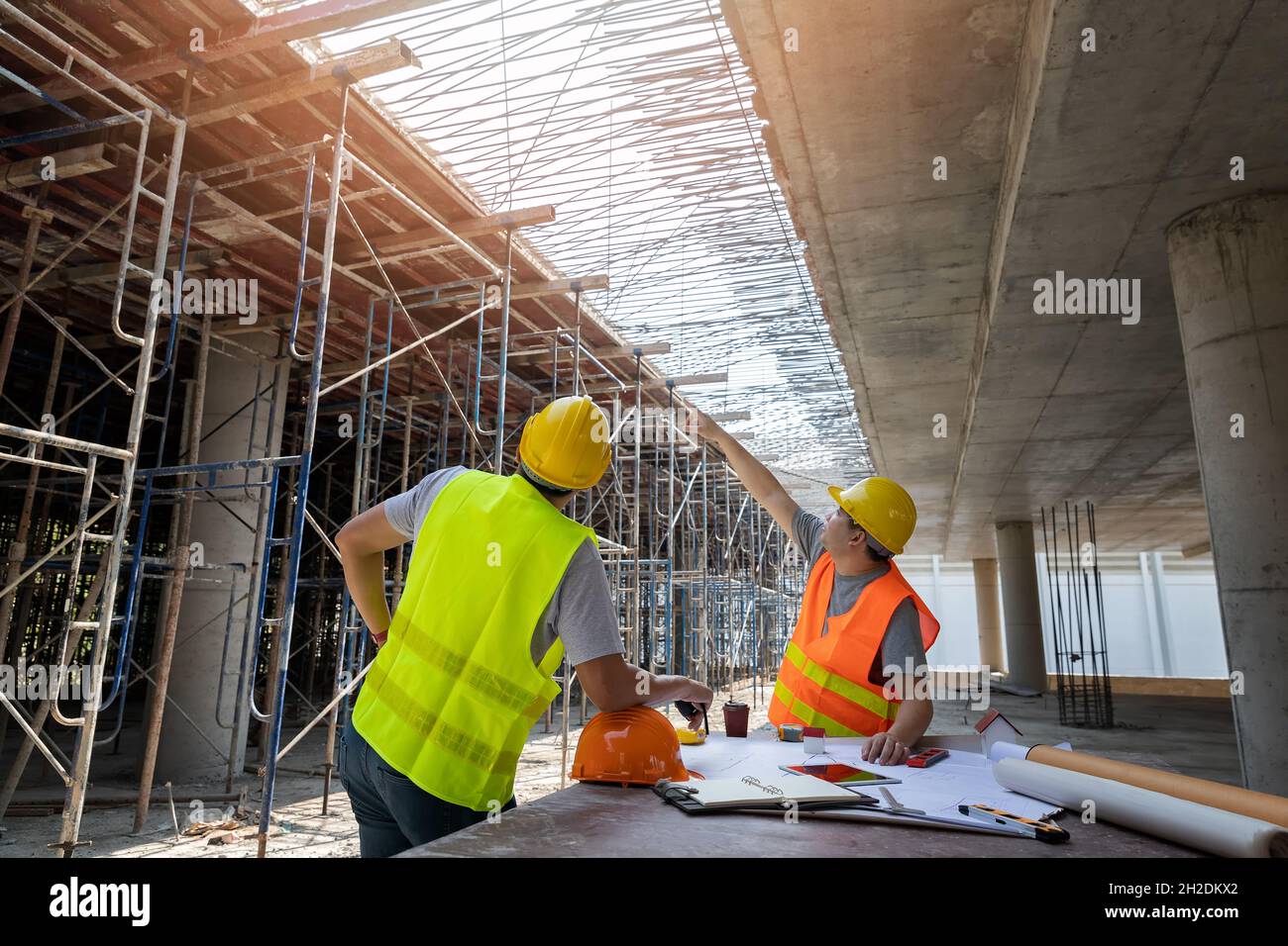 Ingegnere che discute con il caposquadra circa il progetto nel cantiere di costruzione. Ingegnere e architetto che lavora presso il cantiere con stampa blu. Foto Stock