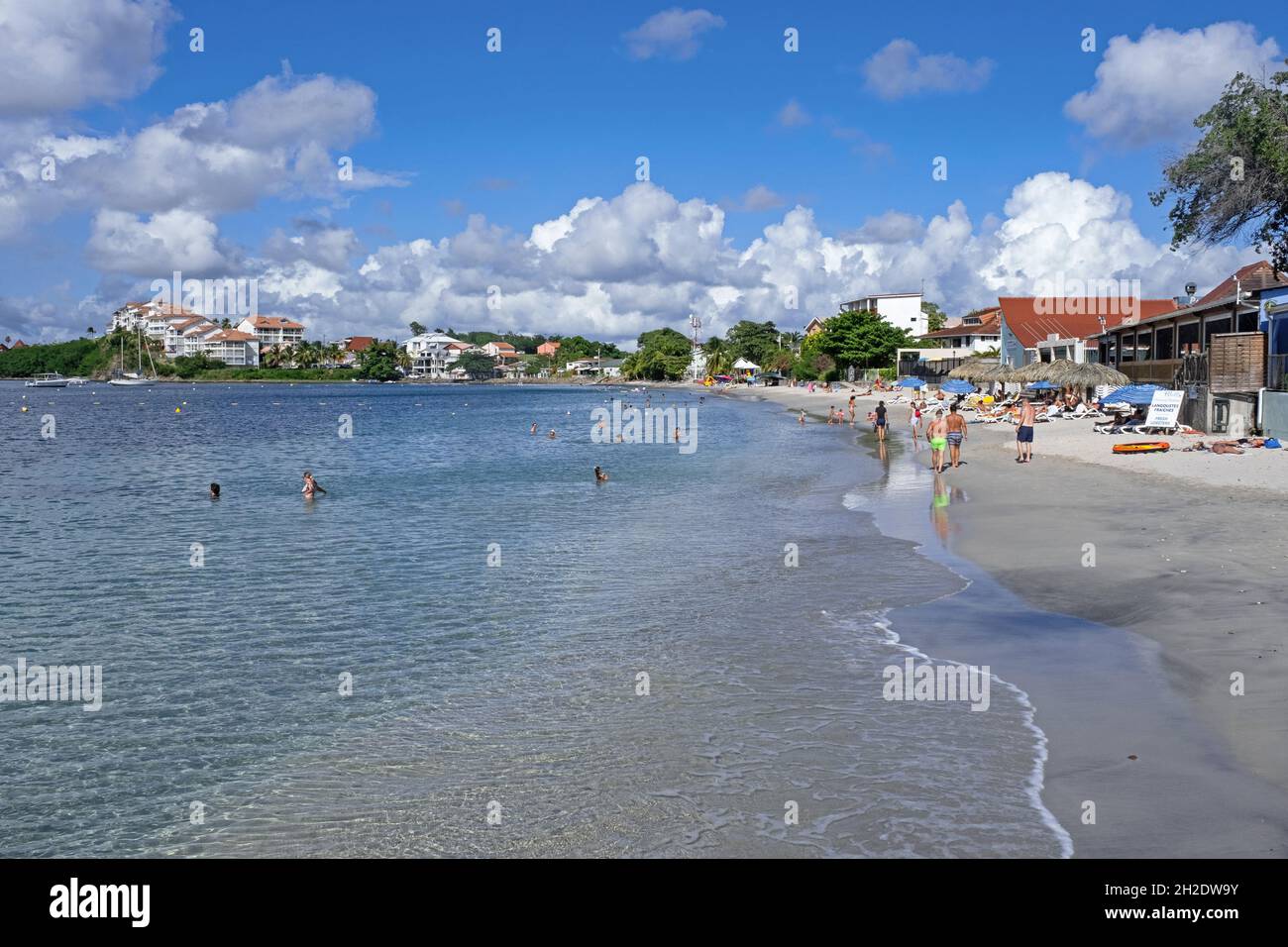 Turisti sulla spiaggia sabbiosa di Anse Mitan, spiaggia principale di Les Trois-Ilets sull'isola francese della Martinica nel Mar dei Caraibi Foto Stock