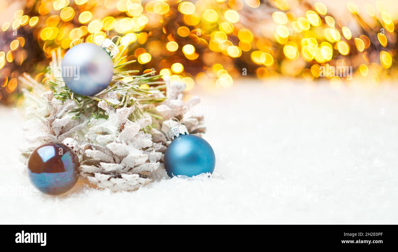 Composizione natalizia con coni nella neve, palline blu e ghirlanda con luci. Foto Stock