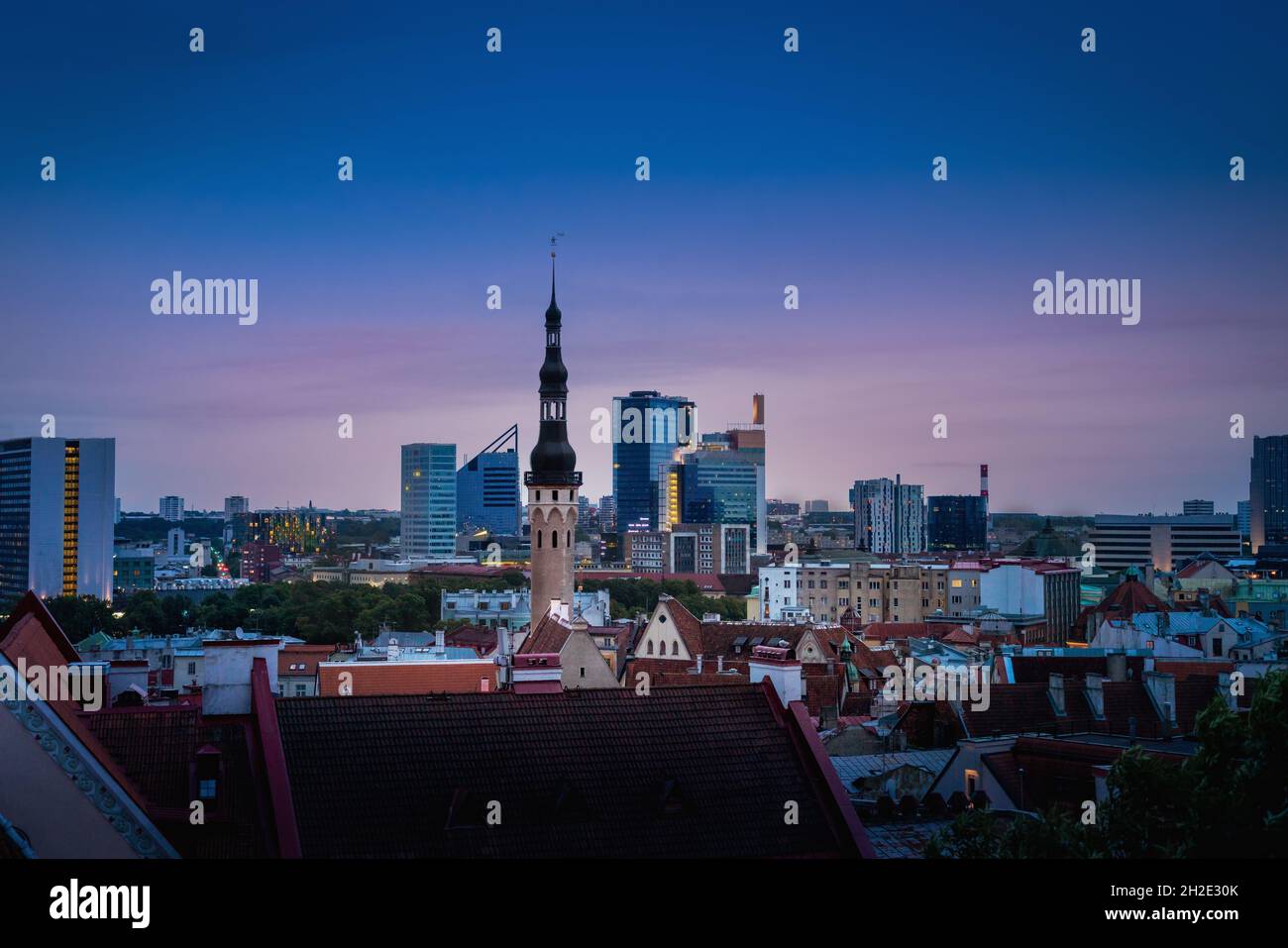 Skyline di Tallinn al tramonto con la Torre del Municipio e gli edifici moderni del Centro Città sullo sfondo - Tallinn, Estonia Foto Stock