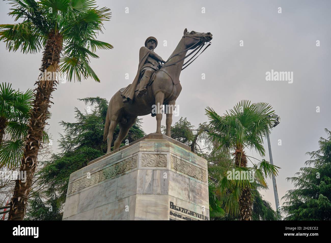 Ataturk fondatore della Repubblica Turca nel centro di Bursa (heykel) durante il tempo piovoso e coperto con bandiera turca e scultura ricoperta da alberi Foto Stock