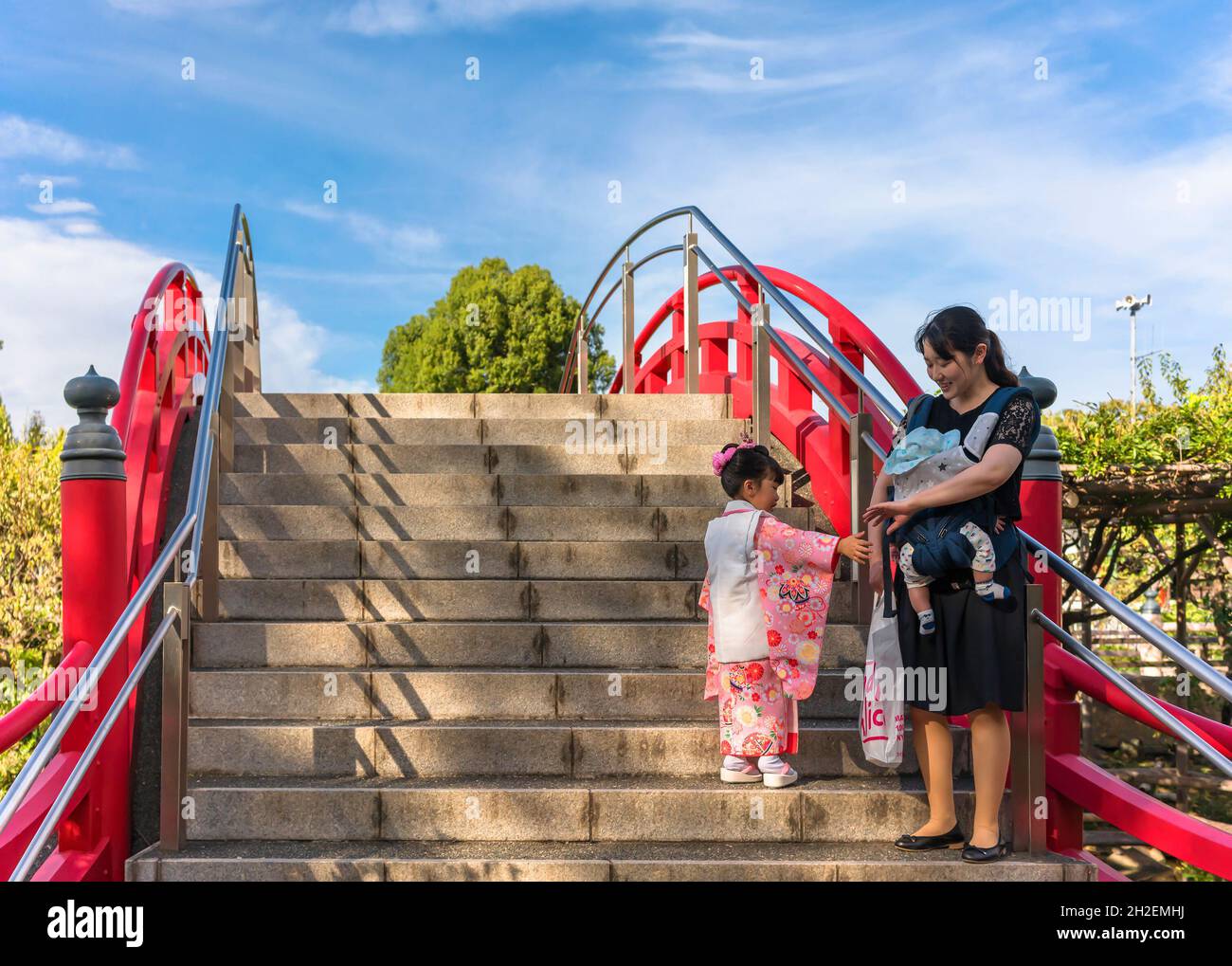 tokyo, giappone - ottobre 26 2019: Bambina in kimono con sua madre e un bambino su un tradizionale ponte taiko bashi rosso nello shintoist Kameido Tenj Foto Stock